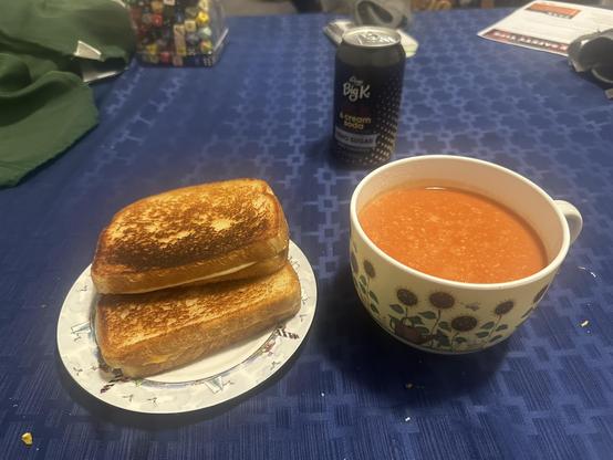 A bowl of tomato soup made with proper milk and a plate with a pair of cheddar and mozzarella grilled cheese sandwiches!